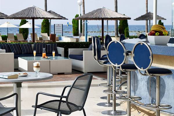Außenbereich des Atlantica Miramare Beach Hotels mit Bar, Tischen und Stühlen.