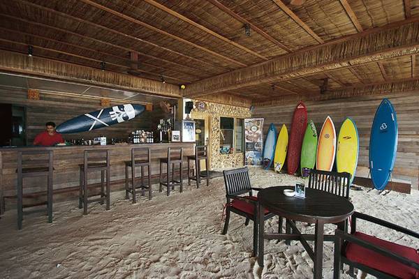 Strandbar des Cinnamon Dhonveli Maldives mit Barhockern und bunten Surfbrettern