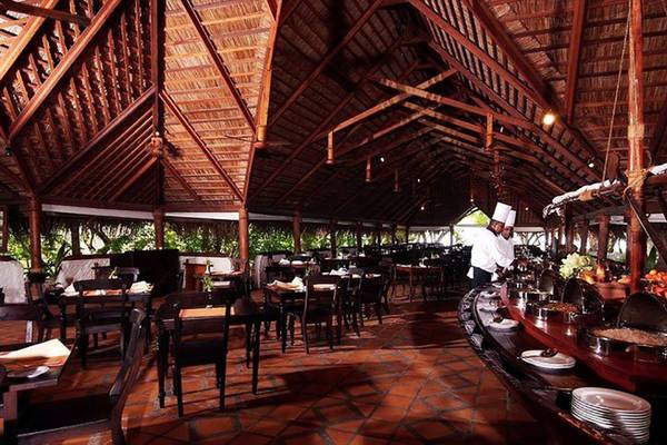 Innenansicht des Restaurants im Cinnamon Dhonveli Maldives, mit voll besetzten Tischen und einem Koch, der Speisen serviert.