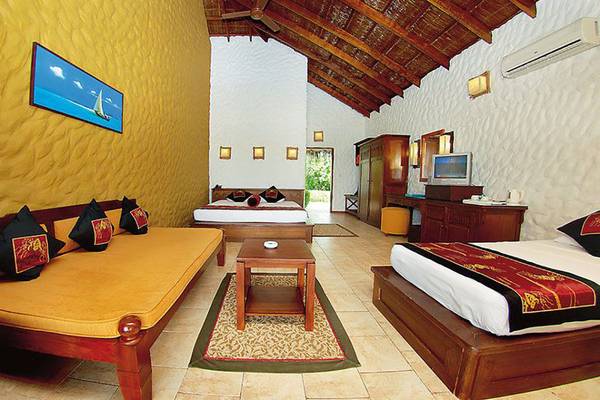 Doppelzimmer im Cinnamon Dhonveli Maldives mit zwei Betten, Sofa und Tisch.