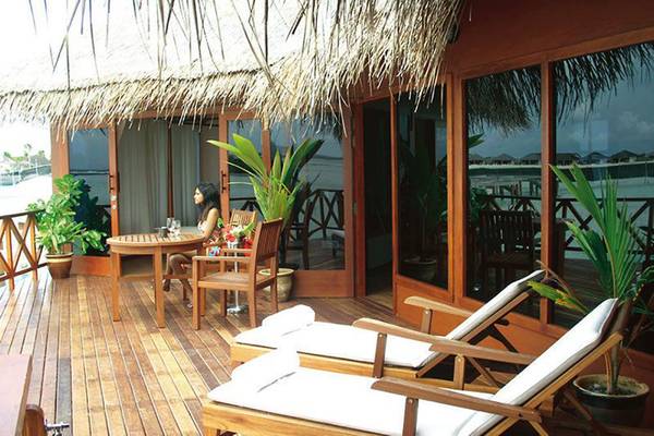 Eine Frau sitzt auf der Terrasse eines Hotels mit Blick auf das Meer.