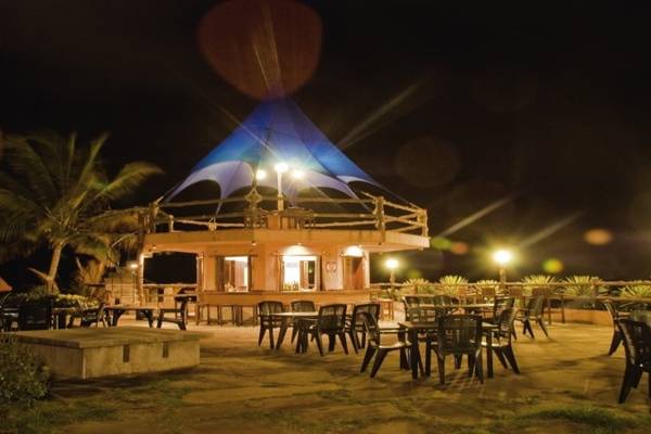 Außenbereich des Bahari Beach Hotel bei Nacht mit Tischen und Stühlen unter einem blauen Zelt.