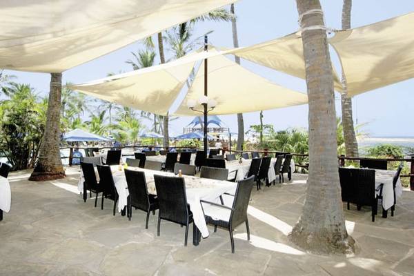 Außenterrasse des Bahari Beach Hotel mit Tischen und Stühlen unter Sonnensegeln.