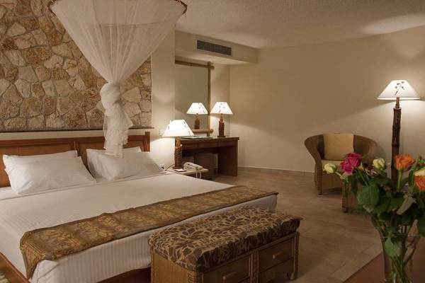 Ein elegantes Hotelschlafzimmer mit einem großen Bett, einem Nachttisch und einem Stuhl mit Kissen.