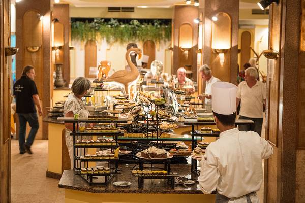 Ein Buffetbereich im Grand Hotel Hurghada mit verschiedenen Desserts und einem Kellner in Uniform.