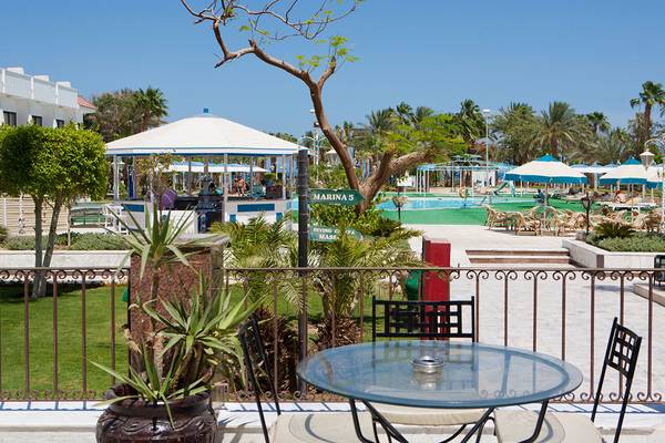 Außenbereich des Grand Hotel Hurghada mit Blick auf eine Terrasse, Pflanzen und einen Swimmingpool.