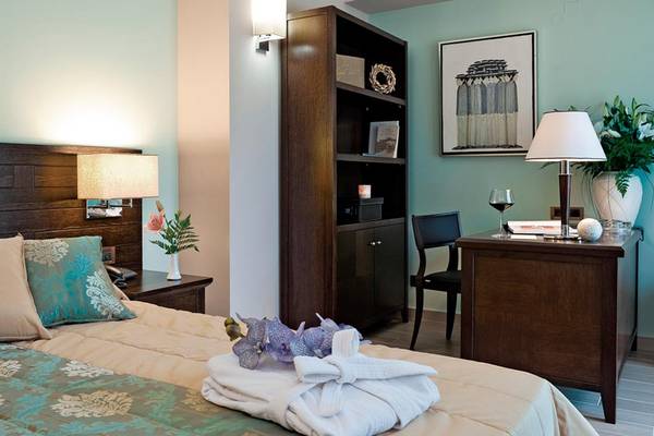 Hotelzimmer im Porto Platanias Beach Resort & Spa mit Bett, Schreibtisch, Lampe und Dekoration.