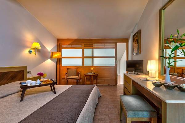 Hotelzimmer im Porto Platanias Beach Resort & Spa mit einem Bett, Frühstückstablett, Schreibtisch und Spiegel.