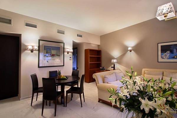 Wohnzimmer im Porto Platanias Beach Resort & Spa mit Tisch, Stühlen, Couch und Blumen.