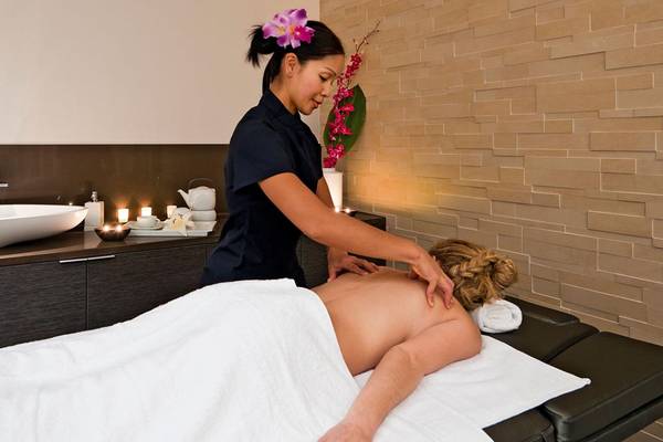 Massage im Porto Platanias Beach Resort & Spa, wo eine Therapeutin eine Rückenmassage an einem Gast durchführt.