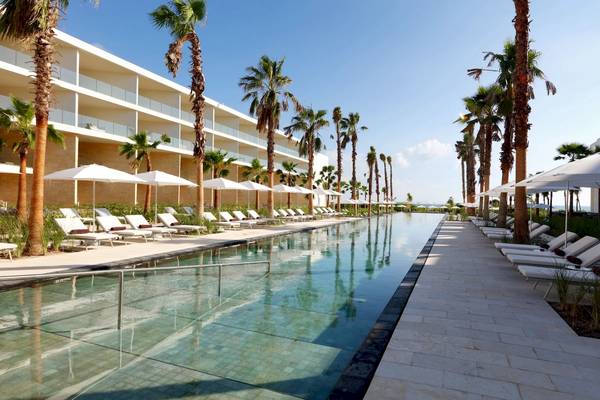 Außenpool des Grand Palladium Costa Mujeres Resort mit weißen Sonnenliegen und Palmen.