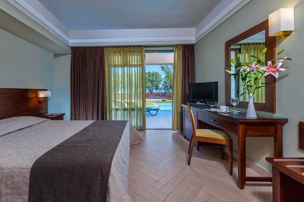 Hotelzimmer im Porto Platanias Beach Resort & Spa mit Bett, Schreibtisch und Aussicht auf den Pool.