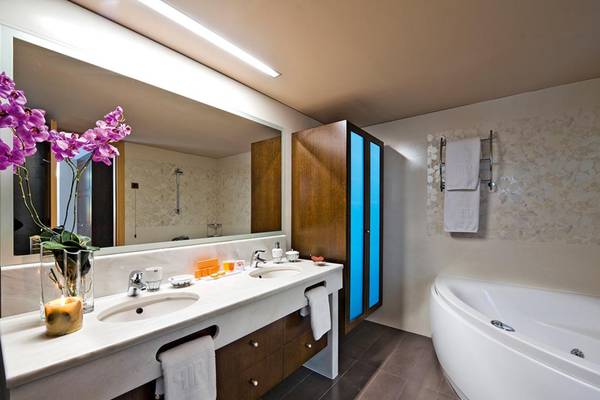 Badezimmer im Porto Platanias Strand Hotel mit zwei Waschbecken, Badewanne und Handtüchern.