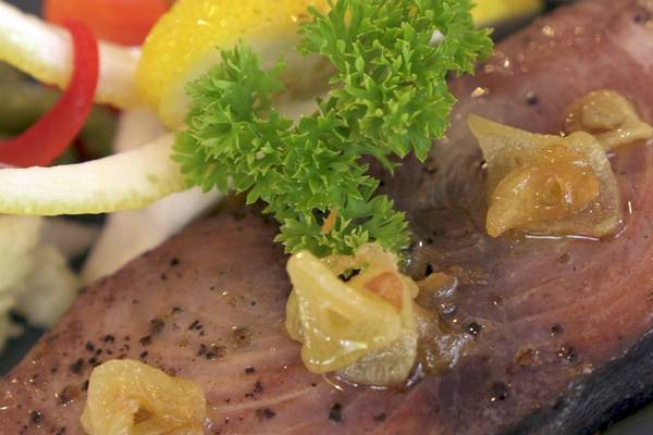 Nahaufnahme von gegrilltem Fisch mit getrockneten Tomaten und frischer Petersilie, serviert im Nika Island Resort & Spa.