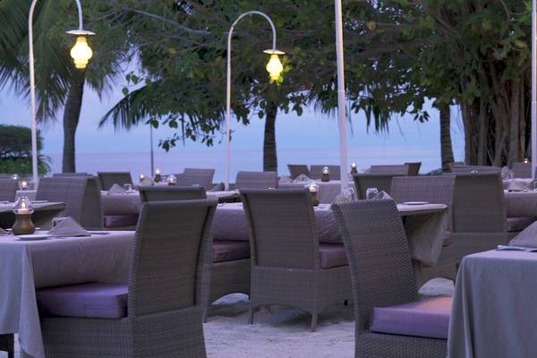 Außenbereich des Nika Island Resort & Spa Restaurants mit abendlicher Beleuchtung und Blick auf den Ozean.