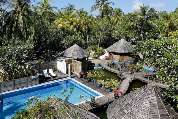 Außenbereich des Nika Island Resort & Spa mit Pool, runden Hütten und Steg