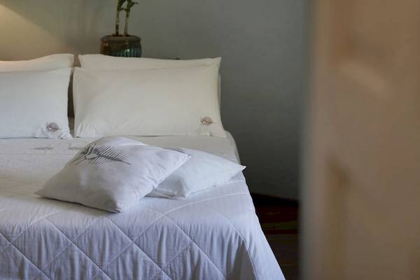 Ein Bett im Zimmer des Nika Island Resort & Spa mit weißen Kissen und Bettwäsche.