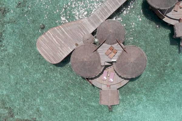 Luftaufnahme des Nika Island Resorts und Spa mit Wasservillen und Sonnenschirmen