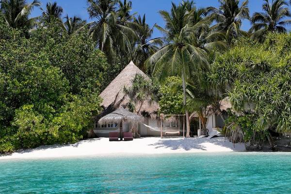 Strandhütte des Nika Island Resorts mit Blick auf den Ozean und Palmen