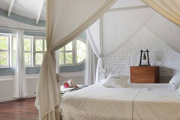 Bett im Zimmer des Nika Island Resort & Spa mit weißem Baldachin und weißen Laken.