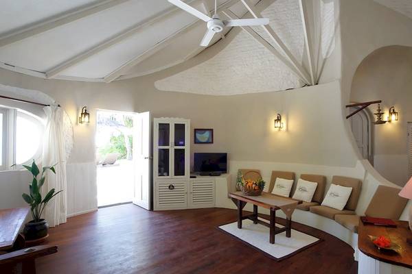 Wohnbereich des Nika Island Resort & Spa mit weißem Interieur, Holzboden und Couchsofa.