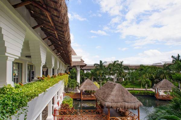 Außenansicht des Grand Sunset Princess All Suites Resorts mit Gebäuden, Dächern und einem See.