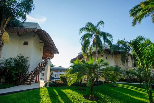 Außenansicht des Grand Sunset Princess All Suites Resorts mit Gebäuden, Palmen und Rasen