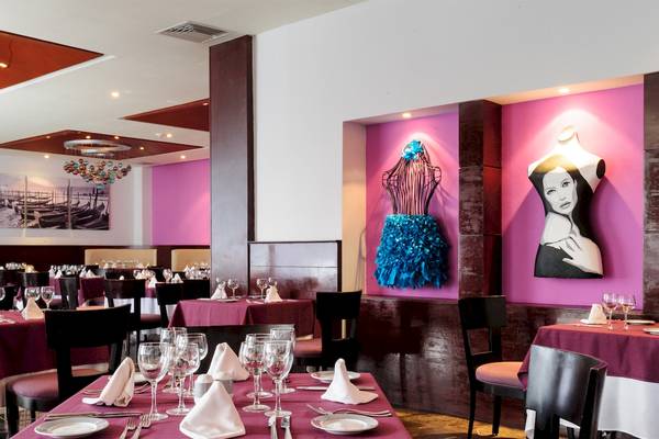 Innenbereich des Restaurants im Grand Sunset Princess All Suites Resort mit Tischdekoration und Kunstwerken an der Wand.