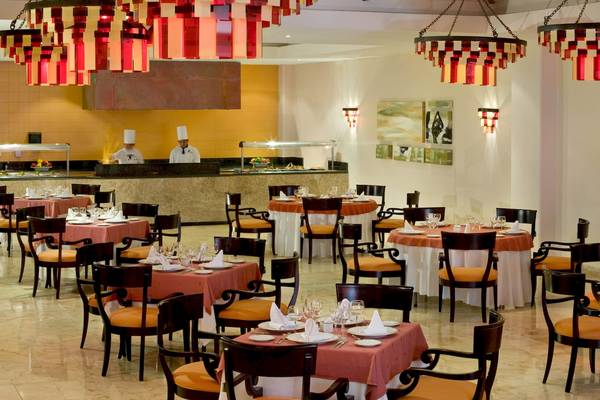 Restaurant im Grand Sunset Princess All Suites Resort mit orange Tischdecken und roten Kronleuchtern.