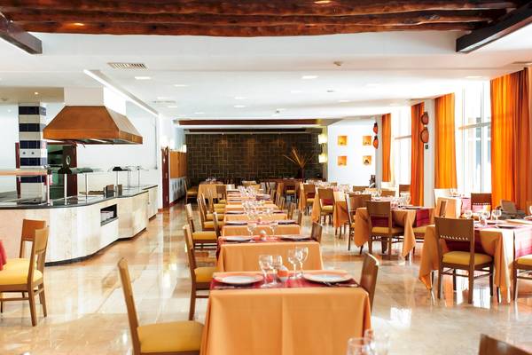Innenansicht des Restaurants im Grand Sunset Princess All Suites Resort mit gedeckten Tischen und Stühlen.