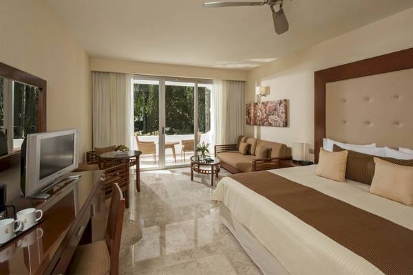 Schlafzimmer im Grand Sunset Princess All Suites Resort mit Bett, Fernseher, Schreibtisch und Terrasse.