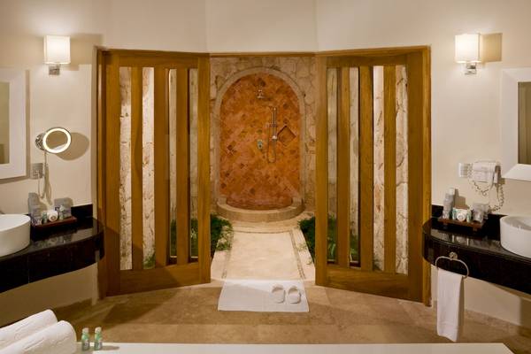 Badezimmer des Grand Sunset Princess All Suites Resorts mit Badewanne, separater Dusche und Holztüren.