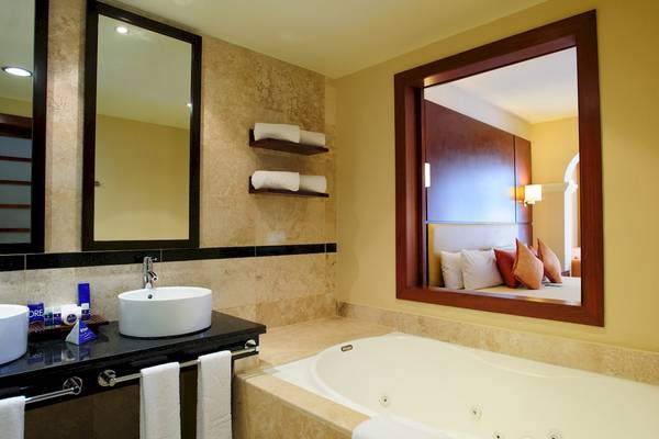 Badezimmer im Grand Sunset Princess All Suites Resort mit Badewanne, Waschbecken und Spiegeln.