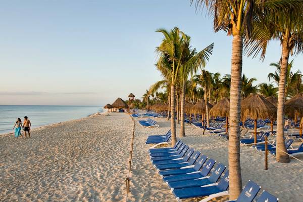 Strand mit blauen Sonnenliegen und Palmen am Grand Sunset Princess All Suites Resort