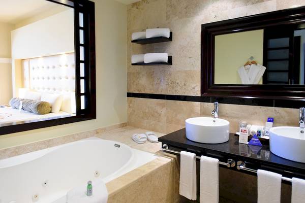 Badezimmer mit Badewanne, Spiegel und Doppelwaschbecken im Grand Sunset Princess All Suites Resort.