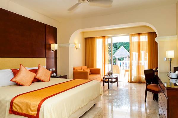 Suite-Zimmer im Grand Sunset Princess All Suites Resort mit Bett, Sofa und Blick auf den Garten.