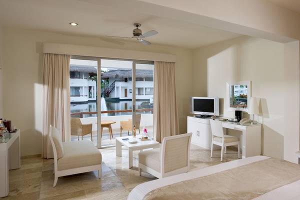 Innenansicht eines modernen Hotelzimmers mit Schlafzimmer, Sitzbereich und Blick auf den Pool.