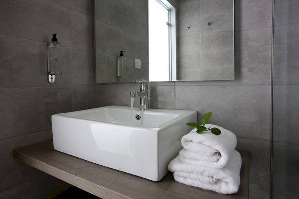 Badezimmer mit einem weißen Waschbecken und einem grauen Spiegel.