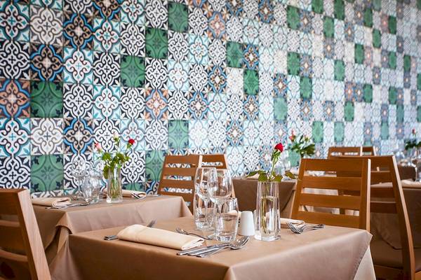 Restaurant-Innenbereich des Bianca Beach Resorts mit blau-grüner Wandfliesen und gedeckten Tischen.