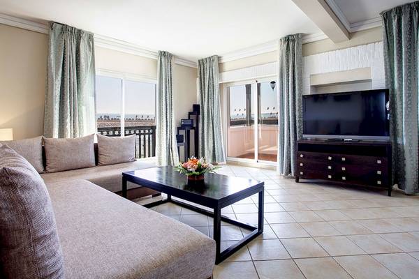Wohnzimmer im Bianca Beach Resort mit einem großen Sofa, einem Tisch mit Blumen und einem Fernseher auf einem Schrank.