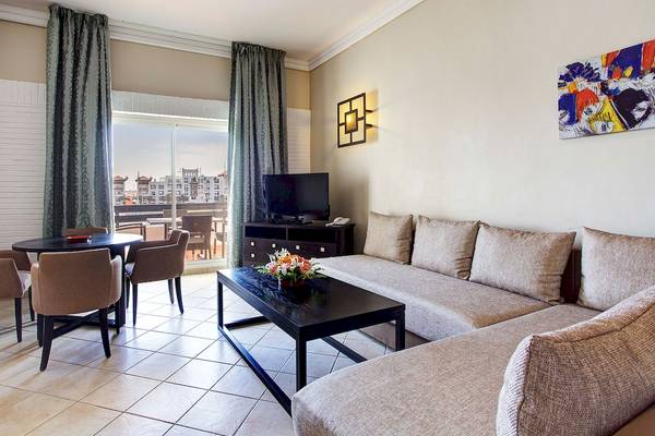 Wohnbereich des Bianca Beach Resorts mit Sofa, Tisch, Fernseher und Blick auf die Stadt.