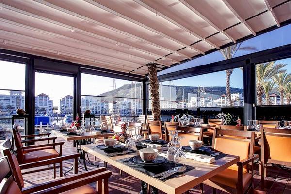 Innenansicht des Restaurants im Bianca Beach Resort mit Tischen und Stühlen, Aussicht auf die Stadt und Berge.
