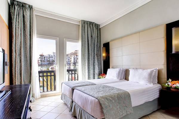 Doppelbettzimmer im Bianca Beach Resort mit Blick auf die Stadt und Balkon.