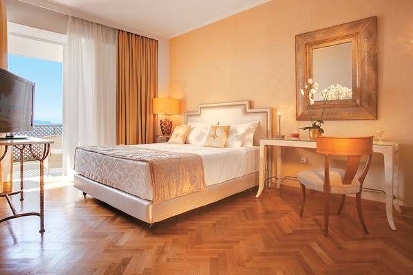 Schlafzimmer im Grecotel Creta Palace mit Bett, Schreibtisch, Stuhl und Fernseher.