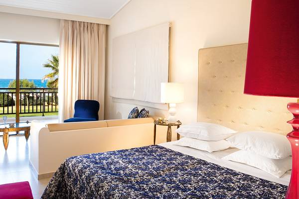 Schlafzimmer im Grecotel Creta Palace mit Blick auf das Meer und einem Balkon.