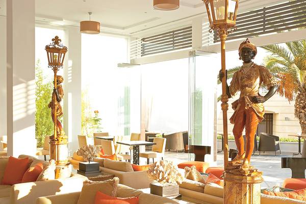 Empfangsbereich des Grecotel Creta Palace mit goldenen Statuen und modernen Möbeln.