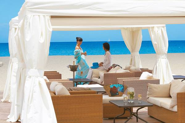 Zwei Frauen unterhalten sich unter einem weißen Zelt am Strand im Grecotel Creta Palace.