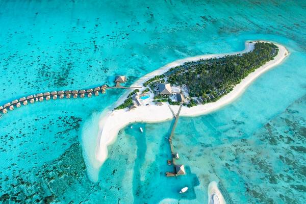 Luftaufnahme des Cocoon Maldives Resorts, das auf einer kleinen Insel liegt, umgeben von türkisfarbenem Wasser.