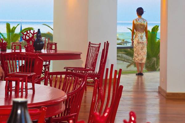 Foto von einer Terrasse des Grecotel Creta Palace mit Blick auf das Meer und roten Stühlen.
