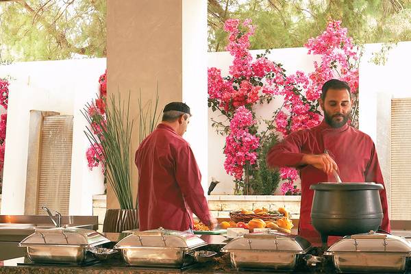 Personal des Grecotel Creta Palace bereitet ein Essen in einem großen Topf zu.
